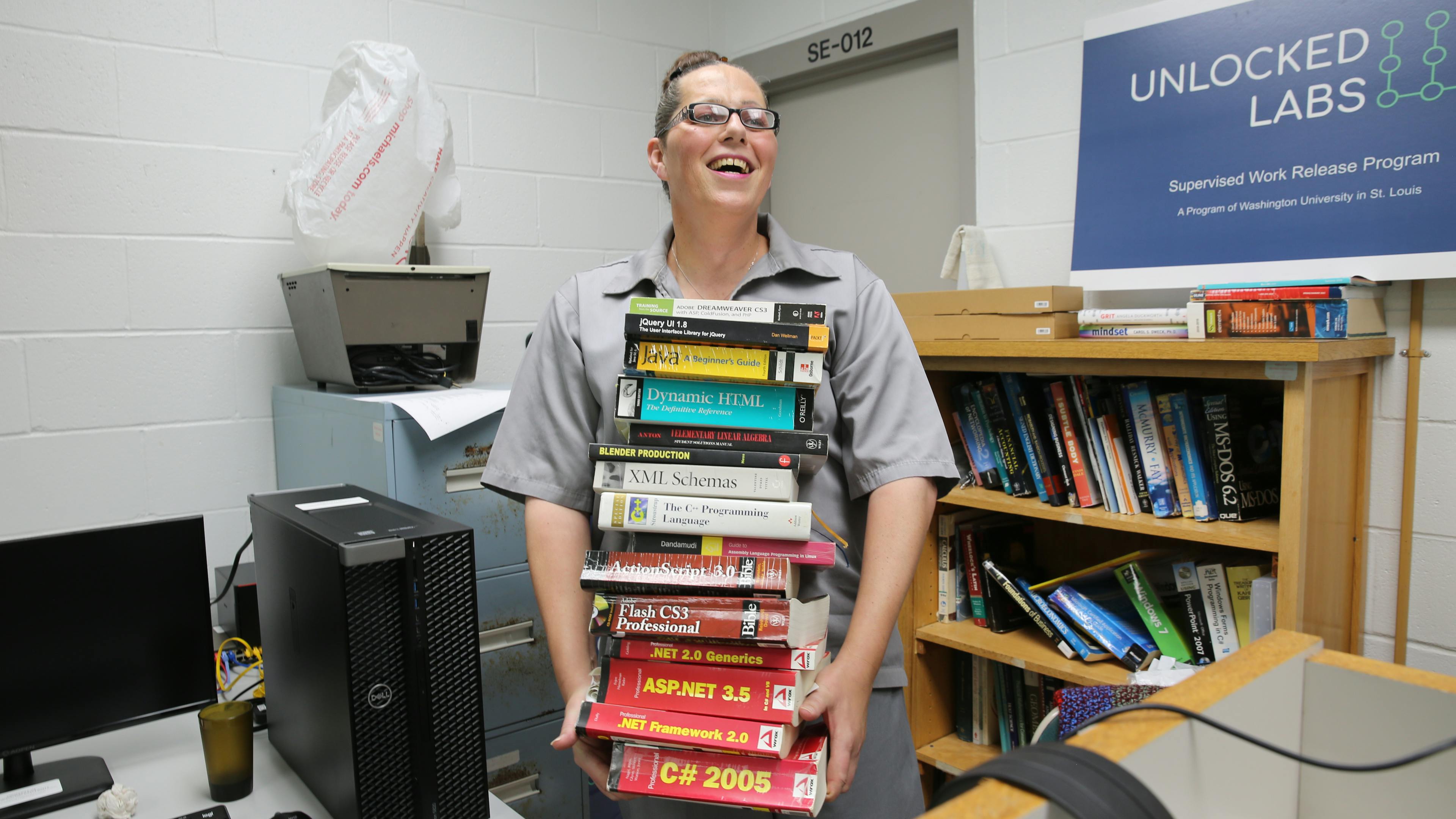 Jessica Hicklin laughing holding stack of 15 computer science textbooks.